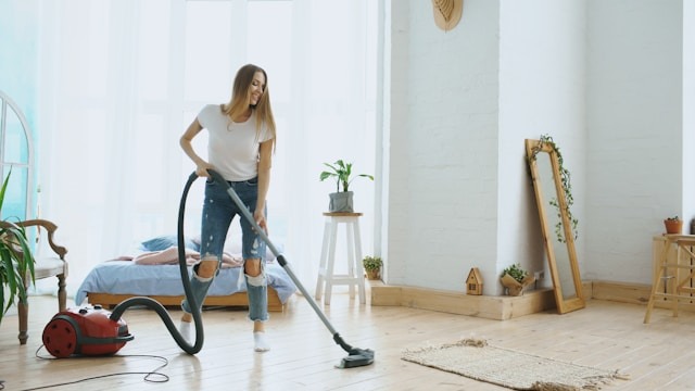 A woman vacuuming her living room, a perfect representation of spring cleaning checklist. Image by Vitaly Gariev via www.unsplash.com
