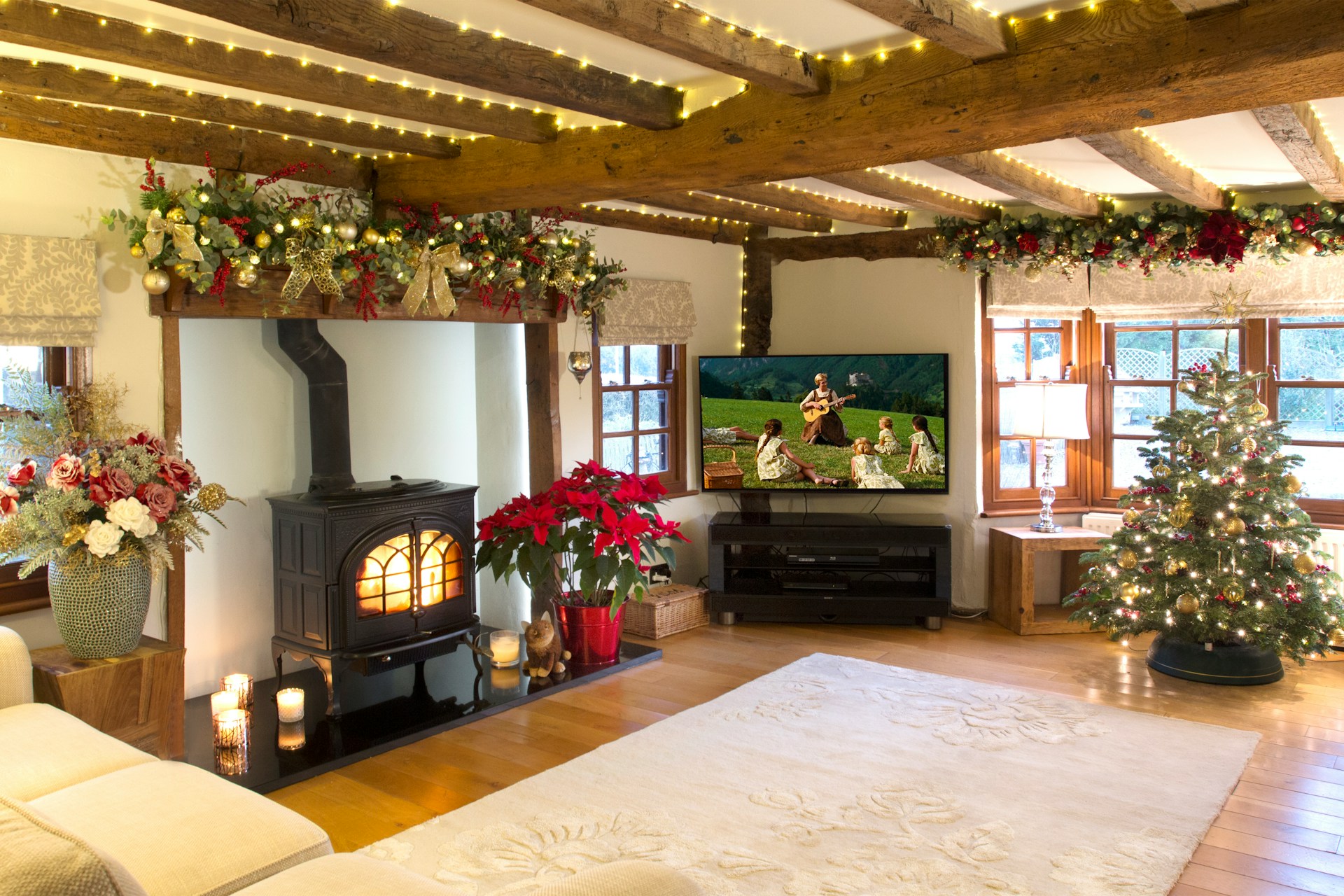Holiday cleaning tips shown in a cozy living room with Christmas tree, glowing fireplace, clean floors, and festive décor creating a warm, guest-ready home. Image by Michelle Cassar via www.unsplash.com